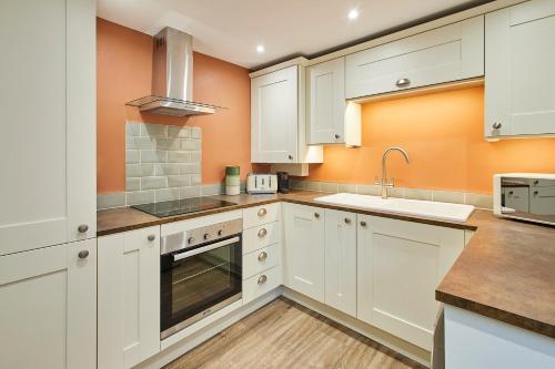 a kitchen with white cabinets and a sink at Host & Stay - Cinnamon Cottage in Barnard Castle