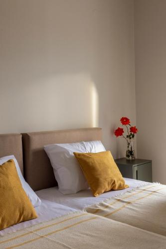 a bed with two pillows and a vase with red flowers at Ursa Minor in Mousata