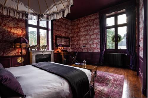 a bedroom with a bed and a fireplace and windows at Château de Maubreuil in Carquefou