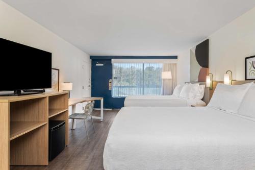 a hotel room with two beds and a flat screen tv at Spark by Hilton Hilton Head Island in Hilton Head Island