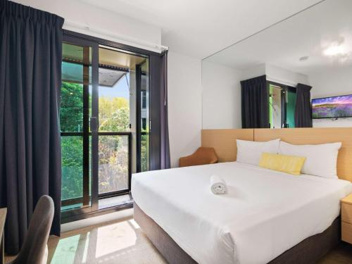 a bedroom with a large bed and a large window at Ibis Darwin Airport Hotel in Darwin