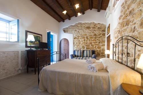 1 dormitorio con cama y pared de piedra en Case Passamonte Agriturismo Resort & Rooms en Chiaramonte Gulfi