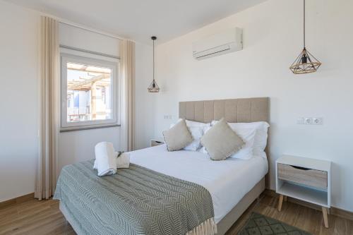 sypialnia z białym łóżkiem i oknem w obiekcie Monte do Cerro w mieście Porto Covo