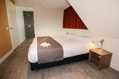 Un dormitorio con una cama grande y una mesa con una lámpara. en Razende Bol en De Koog