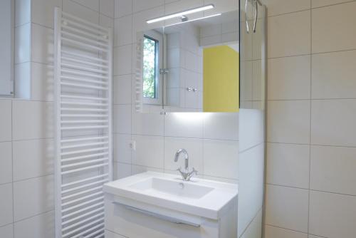 a white bathroom with a sink and a mirror at Razende Bol in De Koog