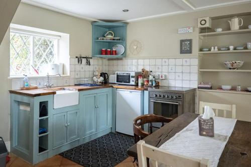 a kitchen with blue cabinets and a table in it at The Rose Cottage in Thomastown