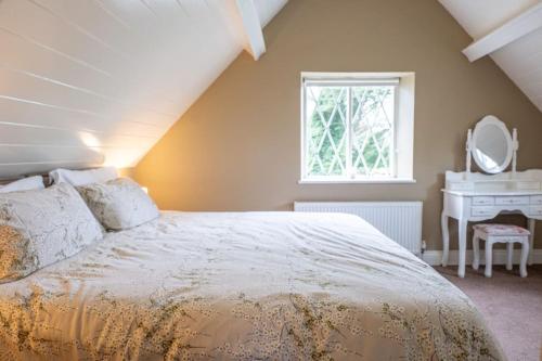 a bedroom with a bed and a desk and a window at The Rose Cottage in Thomastown