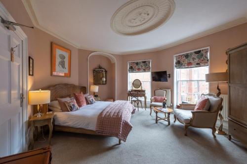 a bedroom with a bed and a chair and windows at Darwin's Townhouse in Shrewsbury