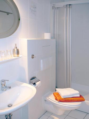 a white bathroom with a sink and a toilet at Gaestehaus Hofer in Bad Birnbach