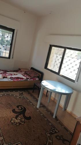 um quarto com uma mesa, uma cama e janelas em حسبان بجانب الجامعه الألمانية الأردنية em Ḩisbān
