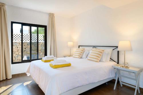 a bedroom with a white bed and a window at Villa Marisol, Los Mojones in Tías