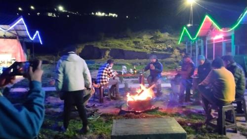 a group of people standing around a fire at night at Kedarnath Tent Prithvi yatra Hotel in Kedārnāth