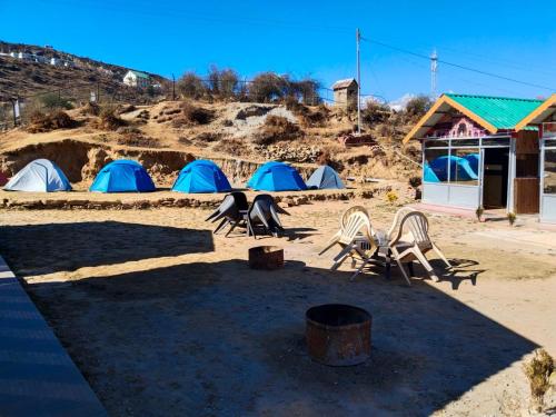un groupe de tentes et de chaises dans la terre dans l'établissement Kedarnath Tent Prithvi yatra Hotel, à Kedārnāth