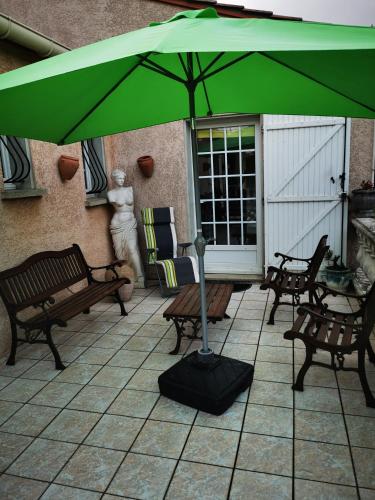 - un parasol vert sur une terrasse avec des bancs dans l'établissement jean guy andrieu, à Labruguière