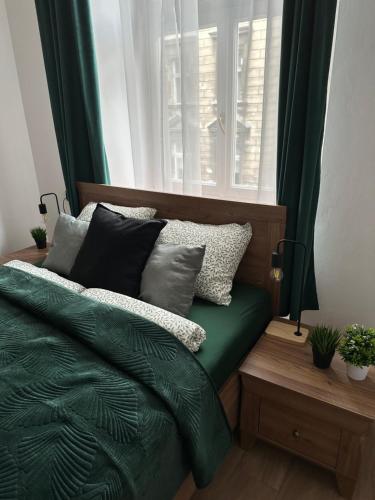 a bedroom with a bed with green sheets and pillows at Wielopole Classy Rooms in Krakow