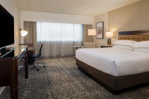 a hotel room with a large bed and a desk at Sheraton Detroit Metro Airport in Romulus