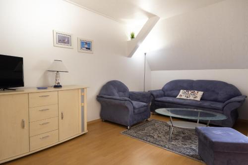 a living room with two blue chairs and a tv at Feriendorf Slawitsch in Bad Sulza