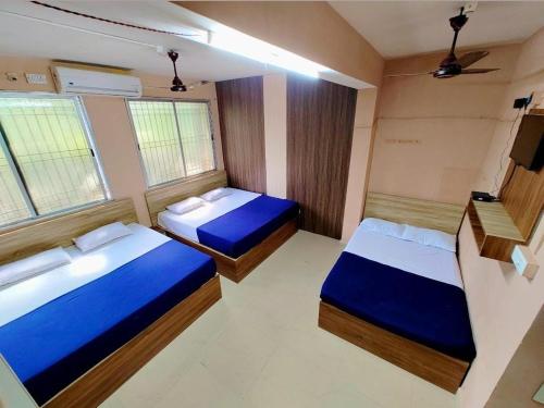two beds in a small room with two windows at Shree lodge in Dandeli