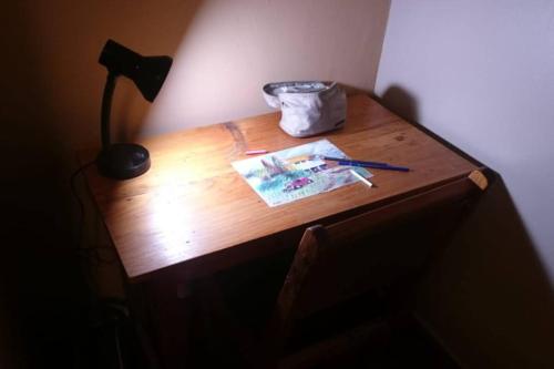 a wooden desk with a lamp and a paper on it at Cozy Guesthouse at Farm Escape in Nairobi