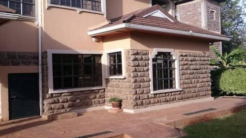 a small brick house with a window in a yard at Cozy Guesthouse at Farm Escape in Nairobi