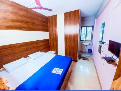 a bedroom with a blue bed and a flat screen tv at Shree lodge in Dandeli