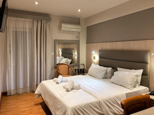 Anemoni Piraeus Hotel في بيرايوس: غرفة نوم بسريرين عليها مناشف بيضاء