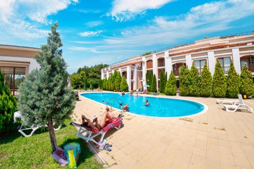 a person sitting in a chair next to a swimming pool at Sea Fort Club Complex in Sveti Vlas