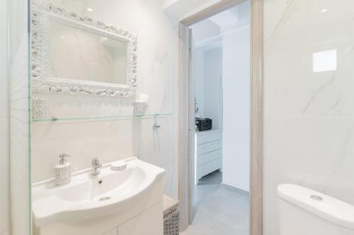 a white bathroom with a sink and a mirror at Seashell by halu! in Nea Fokea