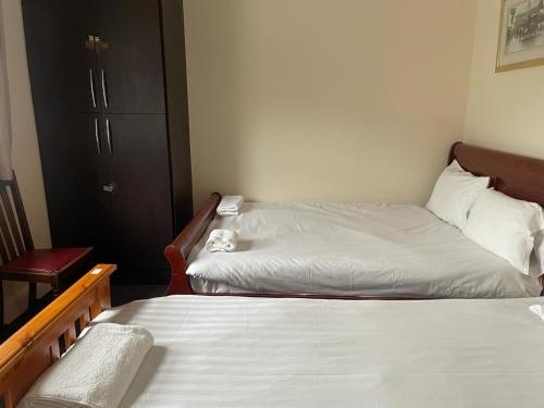 a bedroom with two beds and a chair next to it at Heathrow Stay in Hounslow