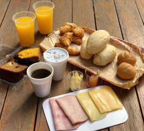 a table with a plate of food with bread and orange juice at Bob Motel in Sao Paulo