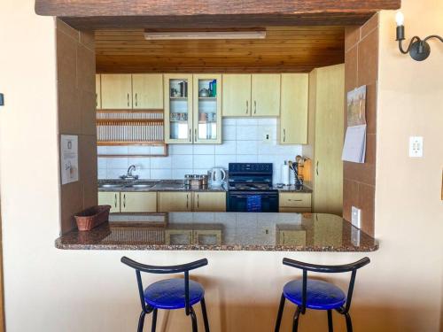 eine Küche mit zwei Hockern an einer Theke in der Unterkunft Family & pet friendly beach house, Kommetjie in Kapstadt