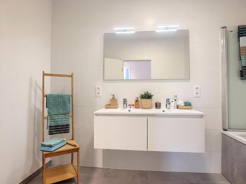 Baño blanco con lavabo y espejo en Magnifique appartement 2 chambres à Liège Ougrée en Seraing