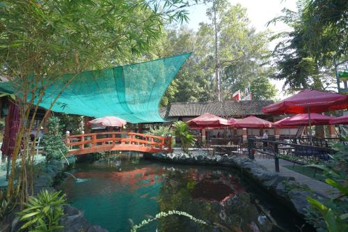 a bridge over a pond with tables and umbrellas at Nhà Hàng Khách Sạn Hòa Bình 2 in Long Xuyên