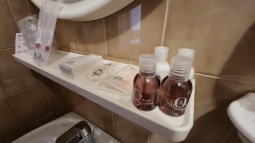 un bagno con due bottiglie su una mensola accanto a un WC di Inter Hotel B&B a Vigo di Fassa