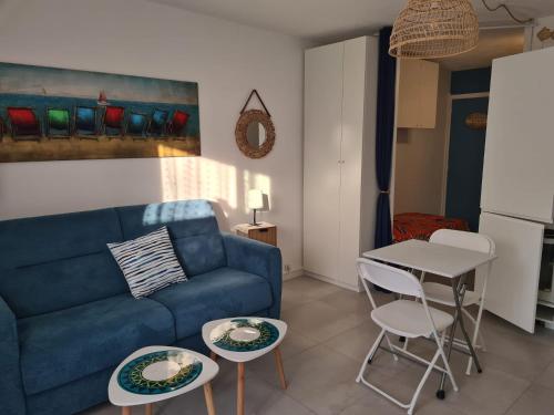 uma sala de estar com um sofá azul e duas mesas em Studio port et mer em Le Grau-du-Roi