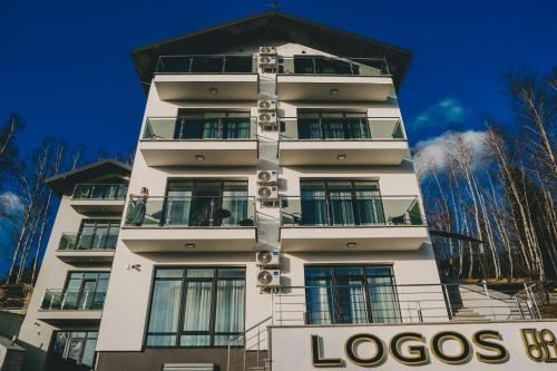 um edifício alto e branco com uma placa à frente. em Апарт-готель LOGOS em Skhidnitsa