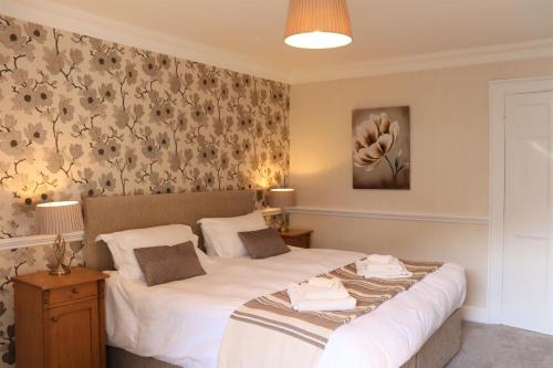 1 dormitorio con 1 cama con sábanas blancas y flores en Portclew House en Pembroke