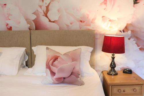 almohada rosa en una cama con lámpara roja en Portclew House en Pembroke