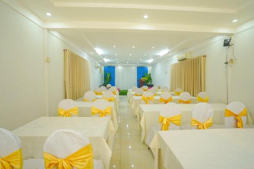 a banquet hall with white tables and yellow bows at Nhà Hàng Khách Sạn Hòa Bình 2 in Long Xuyên
