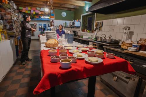 une table dans une cuisine avec des assiettes et des bols de nourriture dans l'établissement Alhue Patagonia Hostel, à San Martín de los Andes