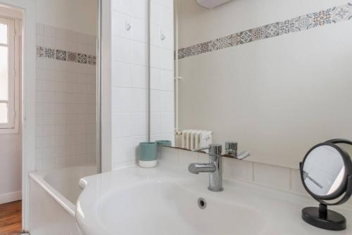 une salle de bain blanche avec une baignoire et un miroir dans l'établissement Eiffel Tower Saint Residence, à Paris