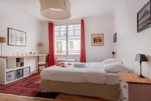 - une chambre avec un grand lit et des rideaux rouges dans l'établissement Eiffel Tower Saint Residence, à Paris