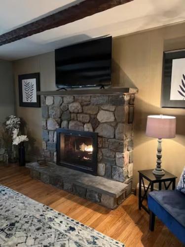 a living room with a stone fireplace with a flat screen tv at Mountain Road Lodge in Tannersville
