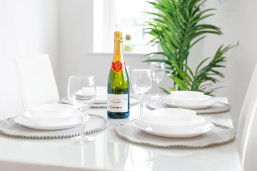 een witte tafel met een fles wijn en glazen bij 2 Bedroom - Deluxe Apt with Free Private Parking - Netflix & Wifi - Top Rated - 52C in Sleightholme