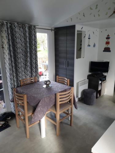 - une table à manger et des chaises dans une pièce avec fenêtre dans l'établissement Mobile home 6 personnes, à Sainte-Reine-de-Bretagne