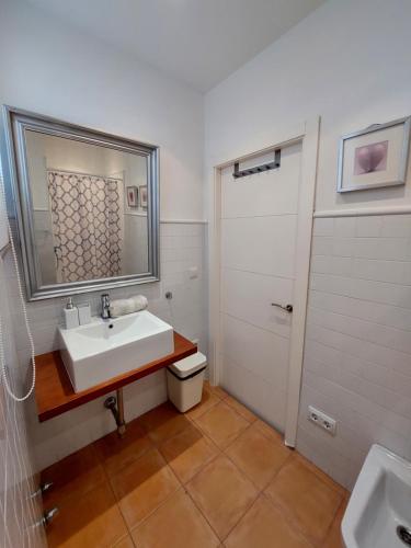 łazienka z umywalką, lustrem i drzwiami w obiekcie Maravilla Apartment w Sewilli