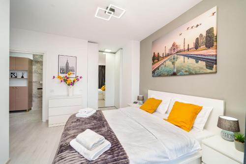 a white bedroom with a large bed with orange pillows at Skyline Sunset View -XCity Tower - By OpenHouse apartments in Timişoara