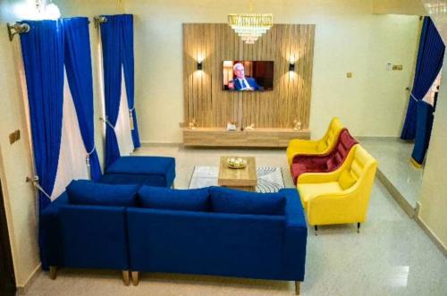 ein Wohnzimmer mit einem blauen Sofa und zwei gelben Stühlen in der Unterkunft Enny'scourt Service Apartment in Akure