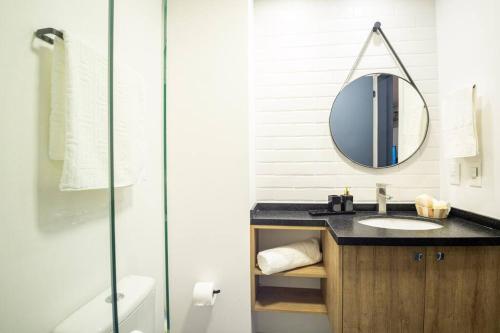 a bathroom with a sink and a mirror at Loft 406 Parque Una + garagem in Pelotas