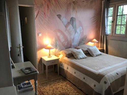 - une chambre avec un lit orné d'une fresque murale représentant des fleurs dans l'établissement Les chaumières du pays d'auge, à Le Breuil-en-Auge